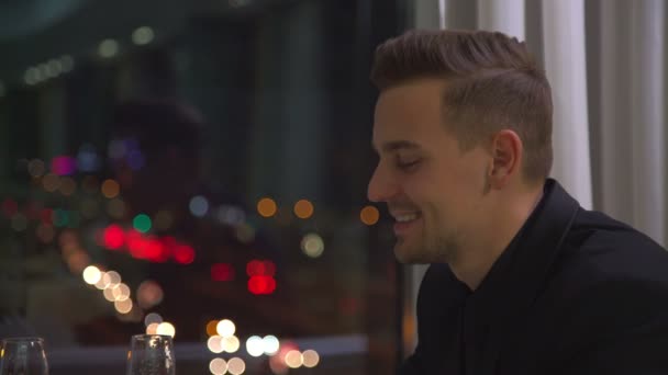 Stylish young man speaking and laughting in front of night city lights — Stock Video