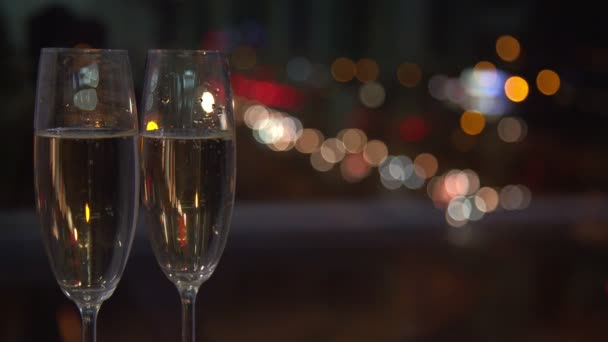 Par de taças de champanhe contra luzes noturnas da cidade no fundo . — Vídeo de Stock