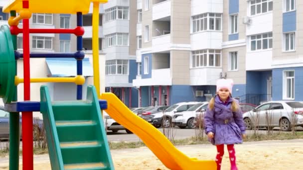 Chica montando una montaña rusa en el patio de recreo — Vídeos de Stock