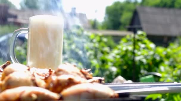 Bier wordt gegoten in een mug tegen de achtergrond van een shish kebab — Stockvideo