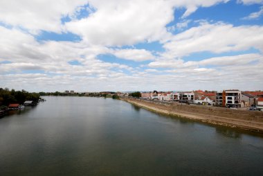 Sremska Mitrovica, Sırbistan, 18 Eylül 2025: Bir zamanlar Roma 'nın başkenti Sirmium olan Sremska Mitrovica' daki tarihi kare Cira Milekiç. Manzara Avusturya-Macaristan mimarisini, astronomik bir saati ve meydanda yürüyen insanları gösteriyor.