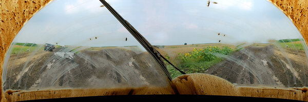 Dirty windshield of a car-of road driving on a road separation through the mud