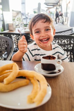 Gülümseyen çocuk bir fincan sıcak çikolatanın tadını çıkarıyor..