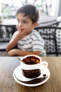 Sevimli çocuk sıcak bir fincan çikolatanın tadını çıkarıyor.