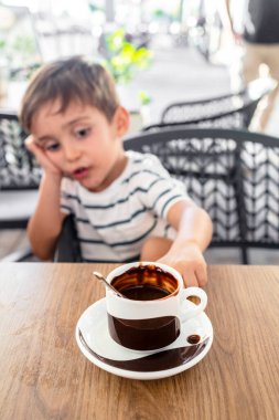 Sevimli çocuk sıcak bir fincan çikolatanın tadını çıkarıyor.