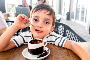 Sevimli çocuk sıcak bir fincan çikolatanın tadını çıkarıyor.