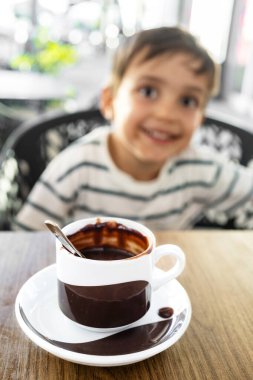 Sevimli çocuk sıcak bir fincan çikolatanın tadını çıkarıyor.