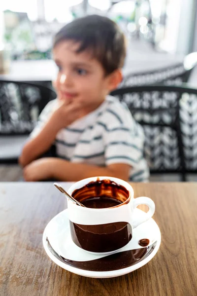 Sevimli çocuk sıcak bir fincan çikolatanın tadını çıkarıyor.