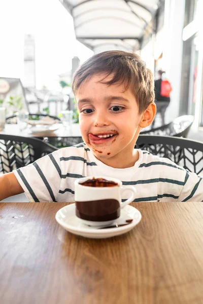 Bir fincan sıcak kakaonun tadını çıkardıktan sonra dudaklarındaki çikolatayı yalıyor..