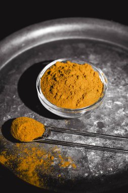 Zıt bir arkaplan üzerinde koyu bir tabakta servis edilen altın zerdeçal tozu.