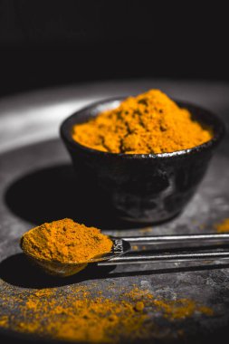 Zıt bir arkaplan üzerinde koyu bir tabakta servis edilen altın zerdeçal tozu.