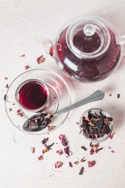 Kurumuş amber yaprağının yanına yerleştirilmiş canlı kırmızı bir çay fincanı bu bitkisel karışımın tazeliğini, rengini ve doğal güzelliğini vurgular..