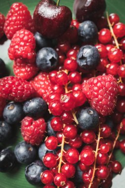 Ahududu, yaban mersini ve kırmızı frenk üzümü içeren lezzetli olgun kırmızı meyvelerin yakın plan fotoğrafı..