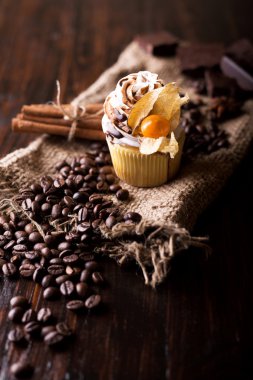 İle beyaz tereyağı krema, çikolata cupcakes kış kiraz koyu ahşap zemin ile dekore edilmiştir. Tarçın ile dekore edilmiş