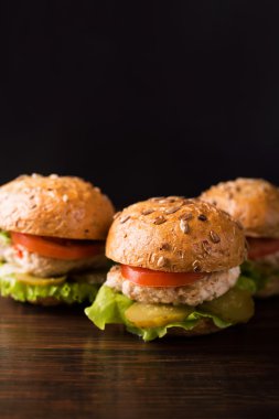 Koyu ahşap bir masa üzerinde üç hamburger