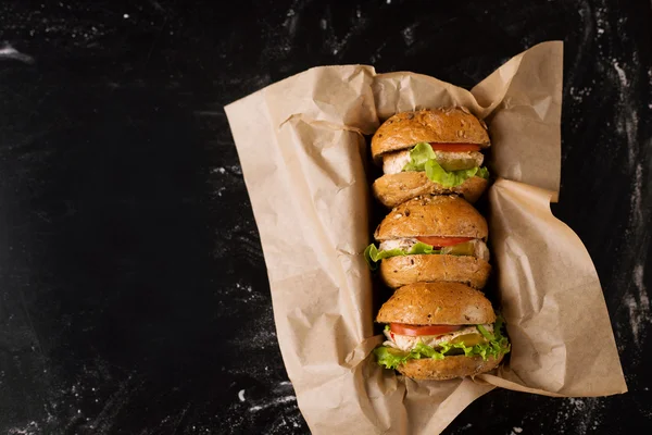 Drie hamburgers op een donkere achtergrond, in de ambacht, bekijken van bovenaf — Stockfoto