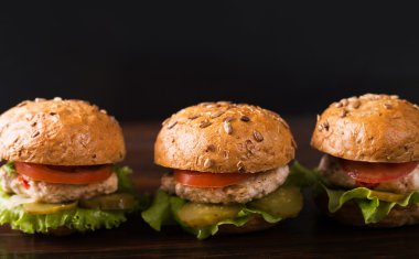 Koyu ahşap bir masa üzerinde üç hamburger