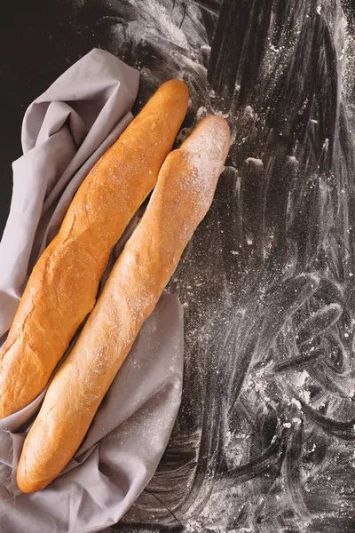 Dos de baguette francesa sobre fondo oscuro con harina — Foto de Stock
