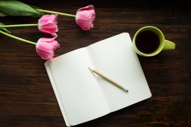 Kahvaltı. Bir fincan çay, çiçekler, notlar, kalem ahşap arka plan üzerinde