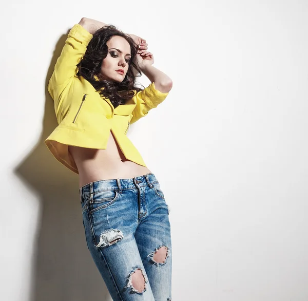 Sexy dziewczyna stylowe dżinsy i żółtą kurtkę w studio — Zdjęcie stockowe