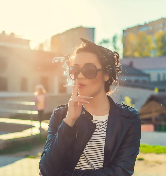 Стильная девушка курит на городском портрете — стоковое фото