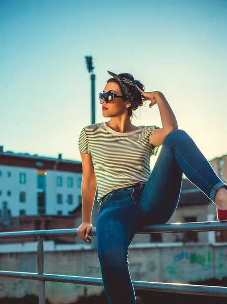 Стильная девушка-хипстер в джинсах и солнцезащитных очках в городе — стоковое фото