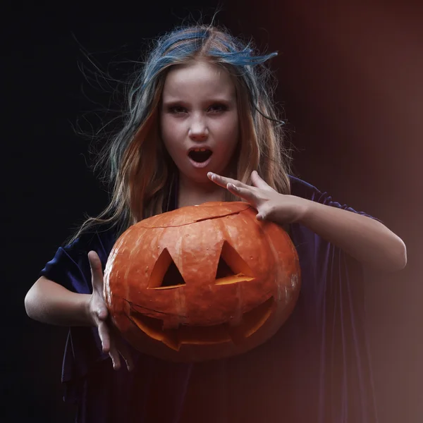 Маленькая девочка в костюме ведьмы на Хэллоуин с тыквой колдуют заклинания — стоковое фото