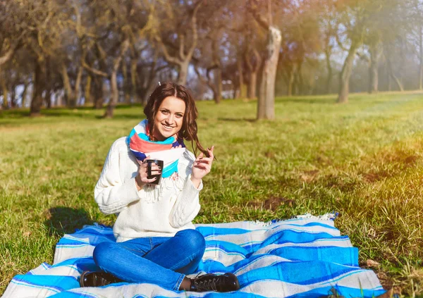 Elegante chica hipster sonriente estudiante con taza de té o café en el parque al aire libre —  Fotos de Stock