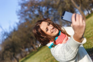 Cep telefonu yapmak selfie ile şık hipster gülümseyen kız öğrenci parkta açık vurdu