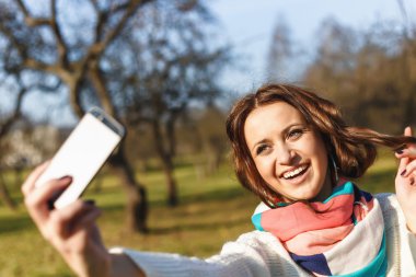 Cep telefonu yapmak selfie ile şık hipster gülümseyen kız öğrenci parkta açık vurdu