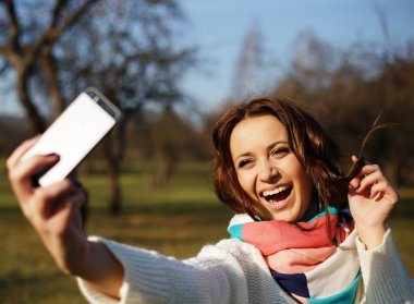 Cep telefonu yapmak selfie ile şık hipster gülümseyen kız öğrenci parkta açık vurdu