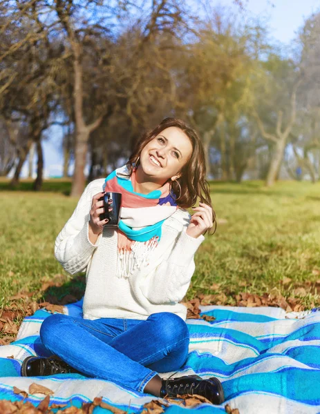 Elegante chica hipster sonriente estudiante con taza de té o café en el parque al aire libre —  Fotos de Stock