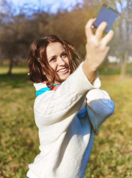 Stylish hipster smiling girl student with the mobile phone make selfie shot in the park outdoor Stock Picture