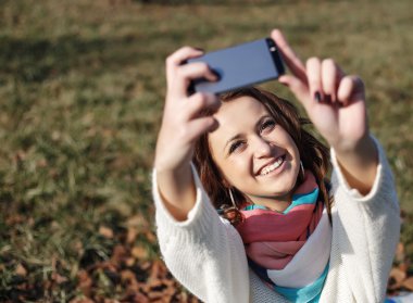 Cep telefonu yapmak selfie ile şık hipster gülümseyen kız öğrenci parkta açık vurdu