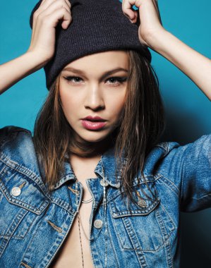 Portre stüdyo çekim güzel hipster genç kızın üzerinde kamera poz seyir Kot ceket bere şapka ile.