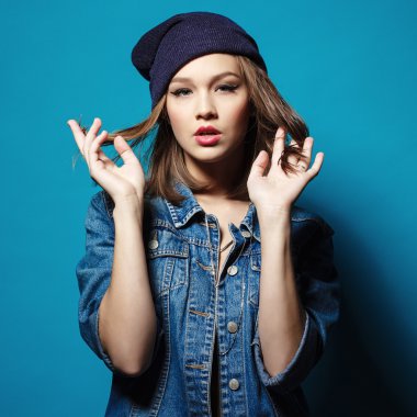 Portre stüdyo çekim güzel hipster genç kızın üzerinde kamera poz seyir Kot ceket bere şapka ile.