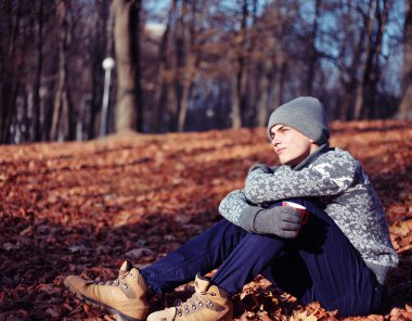 Şık mutlu yakışıklı genç kazak ve fincan çay ya da kahve sonbahar Park ile şapka