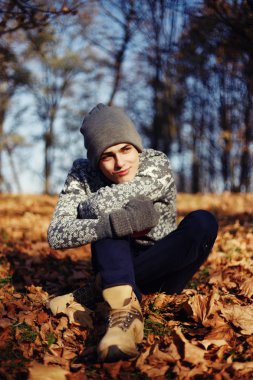 Şık mutlu yakışıklı genç kazak ve fincan çay ya da kahve sonbahar Park ile şapka