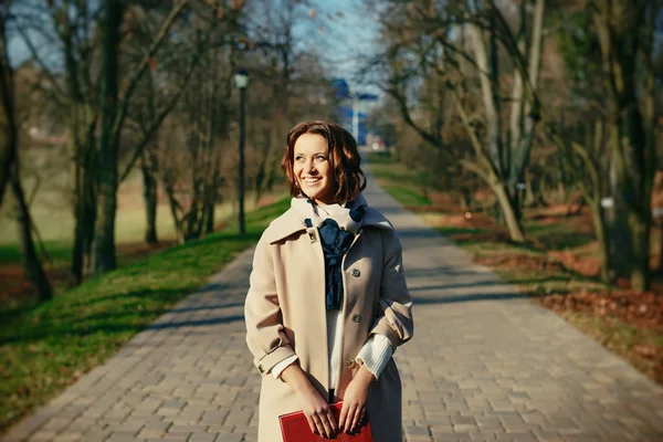 Elegante hipster sorridente studentessa con il libro nel parco all'aperto — Foto Stock
