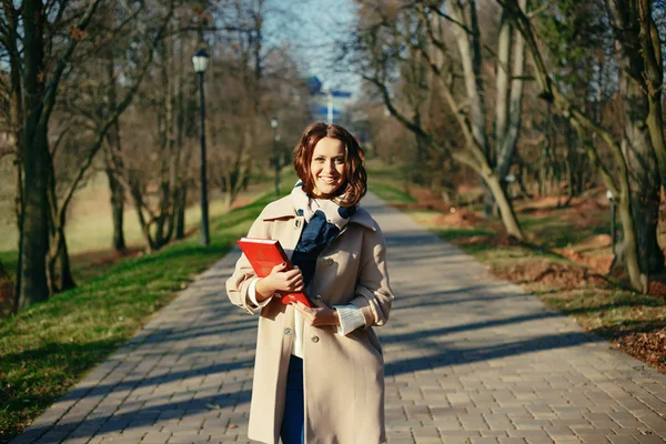 Elegante hipster sorridente studentessa con il libro nel parco all'aperto — Foto Stock