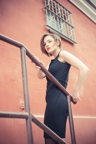 Модель Vogue в чорній сукні на відкритому повітрі біля паркану — стокове фото