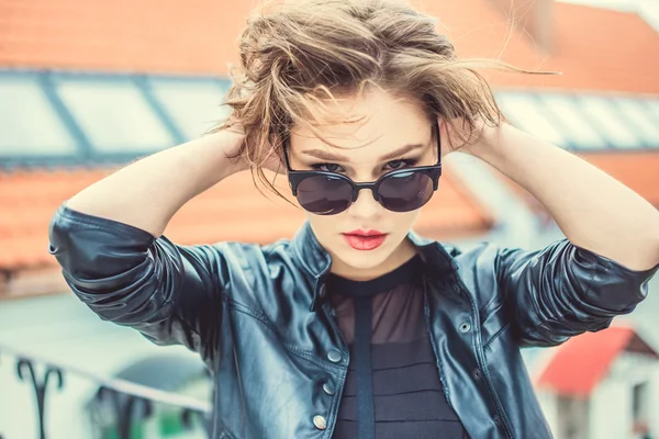 Stylisches Mädchen in Lederjacke und Sonnenbrille im Freien — Stockfoto