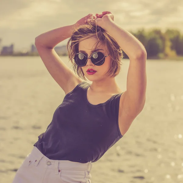 Belle fille sensuelle dans les lunettes de soleil près du portrait de l'eau — Photo