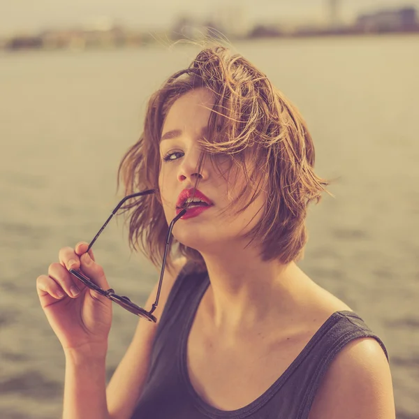 Belle fille sensuelle dans les lunettes de soleil près du portrait de l'eau — Photo