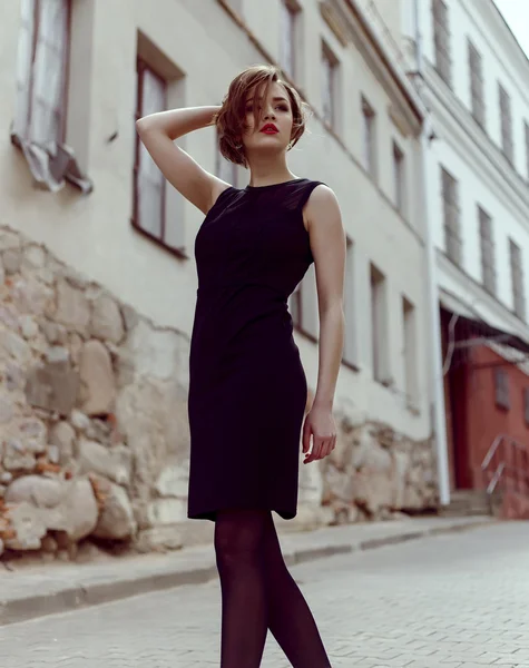 Modemodell im schwarzen Kleid im Freien in der Nähe des Gebäudes — Stockfoto