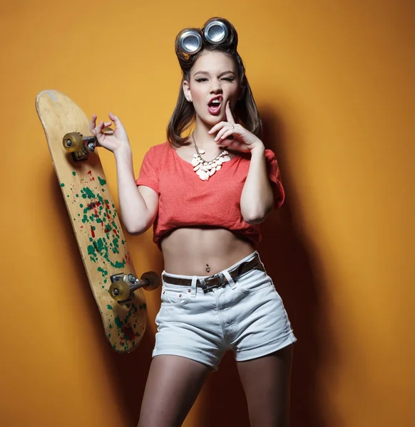 Krásná módní dívka s skateboard před žlutá — Stock fotografie