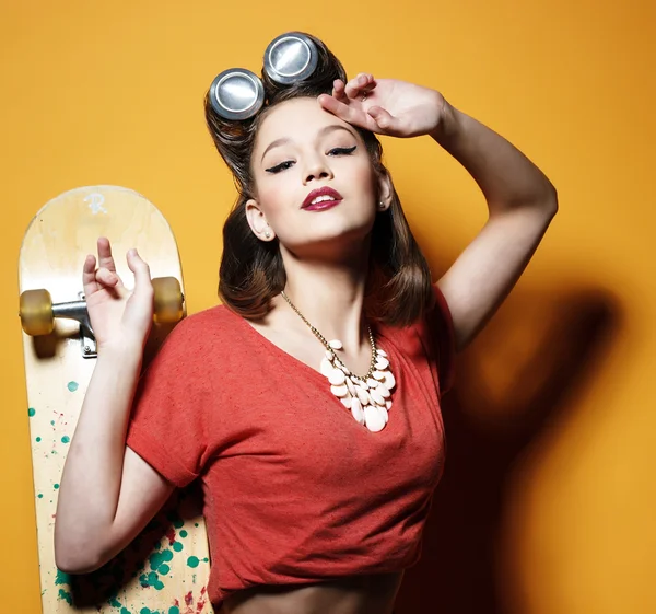 Hermosa chica de moda con un monopatín delante de amarillo —  Fotos de Stock