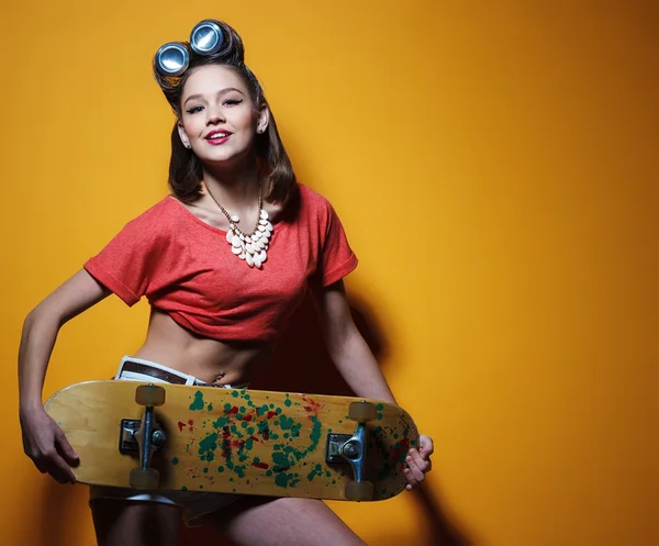 Όμορφο κορίτσι της μόδας με ένα skateboard μπροστά από το κίτρινο — Φωτογραφία Αρχείου
