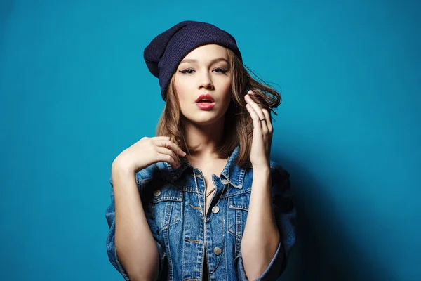 Primer plano de estudio de bastante hipster adolescente con sombrero de gorro con chaqueta vaqueros mirando la cámara posando . —  Fotos de Stock