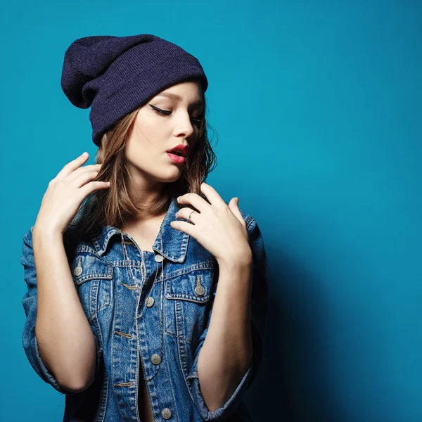 Крупним планом студійний знімок красивої дівчини-підлітка хіпстера з капелюхом у джинсовій куртці, дивлячись на позування камери . — стокове фото
